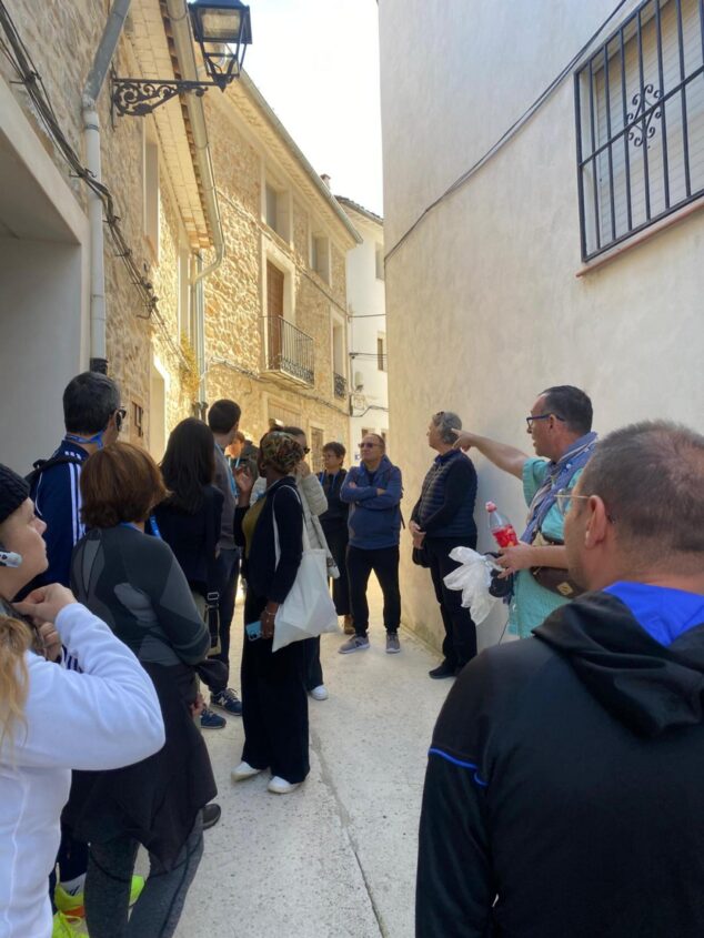 Imagen: Grupo de turistas escuchando a un guía en una calle estrecha de piedra durante una visita urbana en Alpatró.