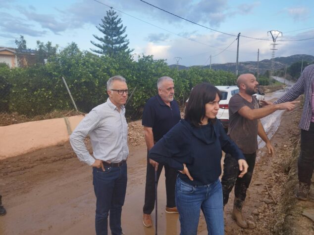 Imagen: La ministra Diana Morant, el alcalde Enrique Moll y otras personas inspeccionando un camino rural embarrado tras las inundaciones en Pego.