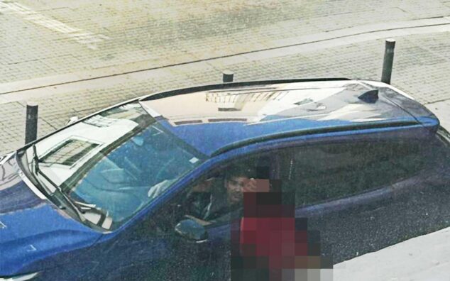 El Grupo Municipal Socialista de Calp denuncia ante la Fiscalía una campaña de odio contra migrantes y acoso a cargos públicos 2 Imagen: Una persona graba desde el exterior al concejal Ximo Perles, que se encuentra dentro de un coche azul.